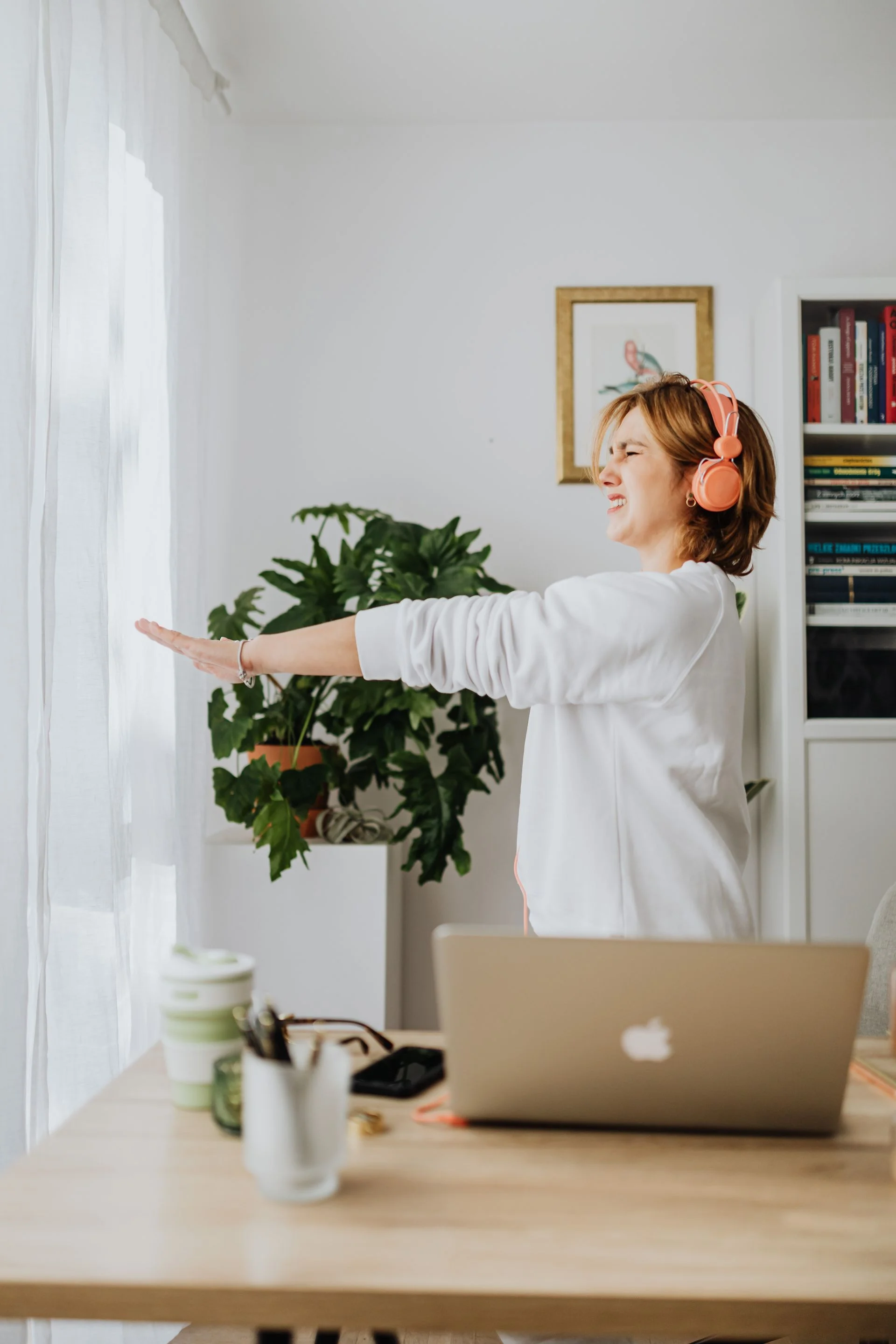 Mulher faz uma pausa para alongar os braços ao lado do computador.