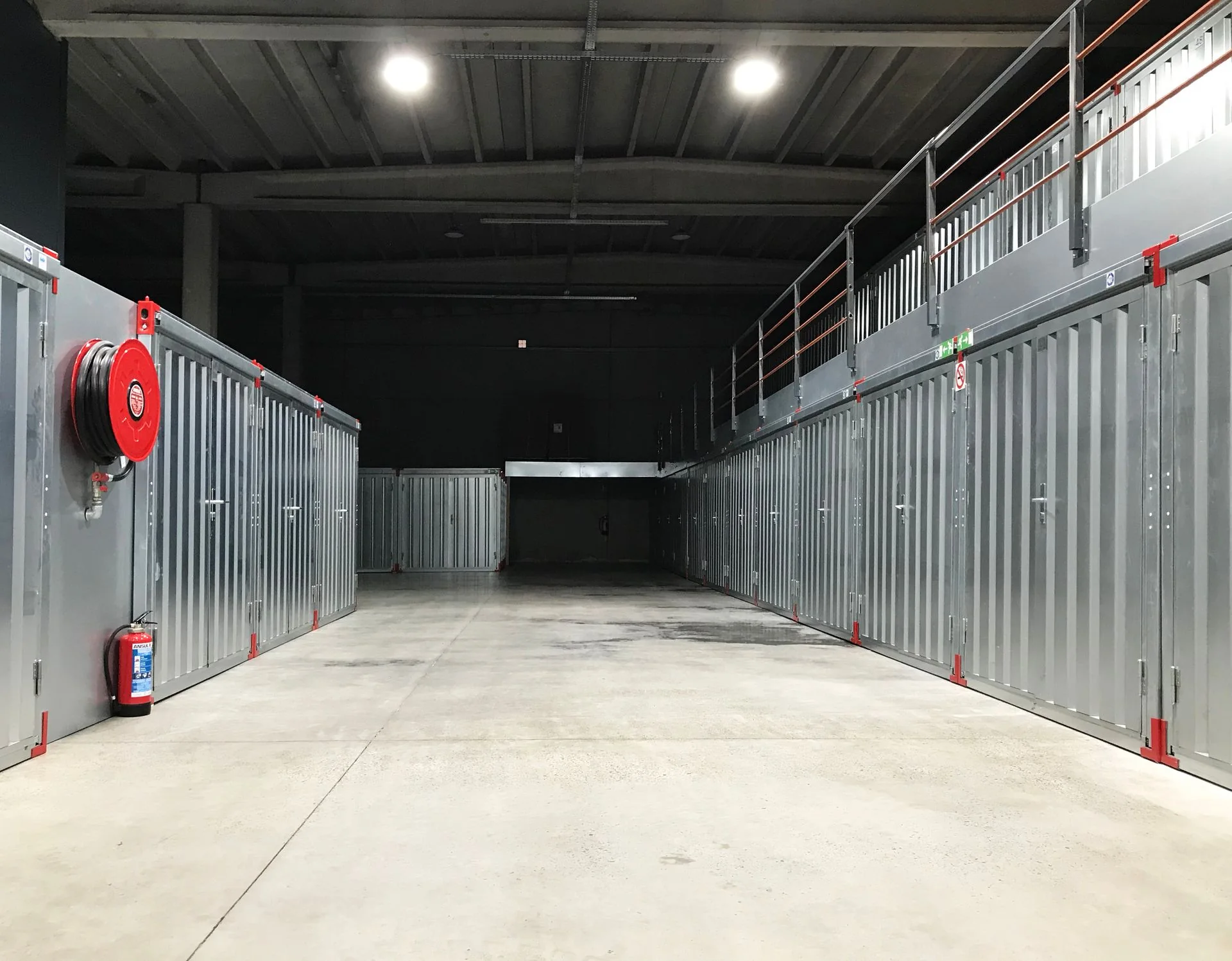 Corredor de instalações de armazenagem com equipamentos de combate a incêndio e sinalização.